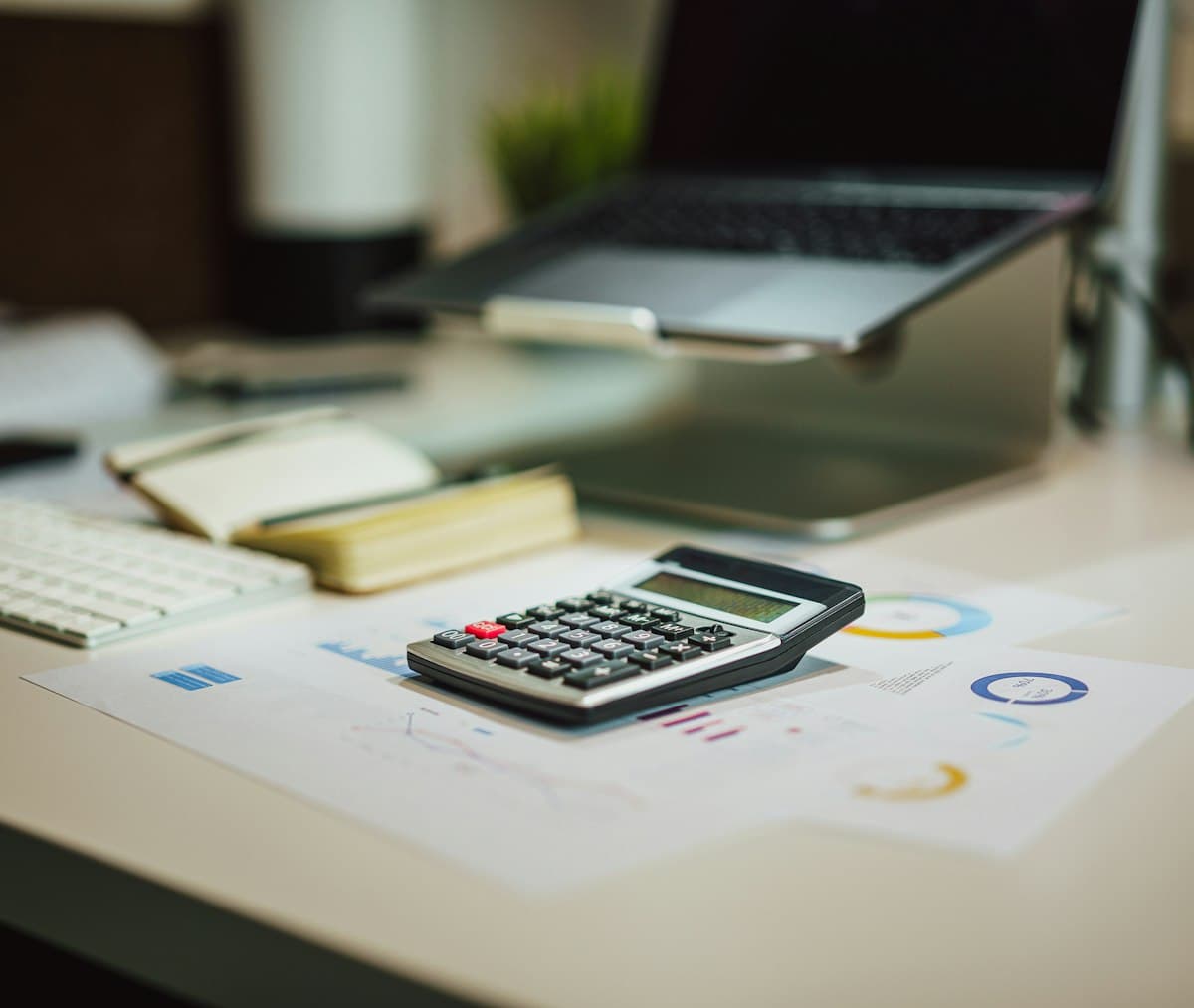 Calculator sitting on a table next to a laptop for working out monthly loan payments